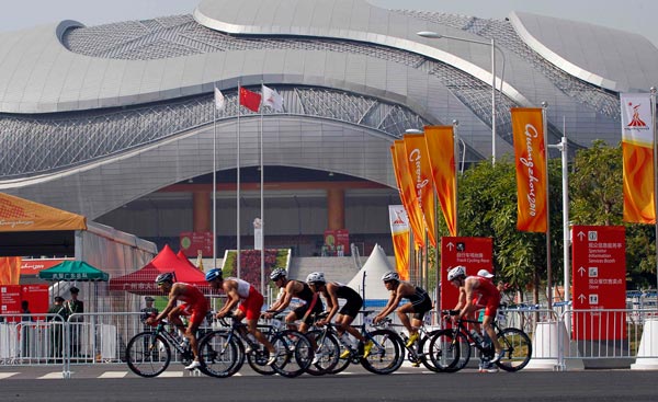 Competitors taking part in the men's triathlon ride past the Guangzhou Velodrome at the 16th Asian Games in Guangzhou, China. (AP)