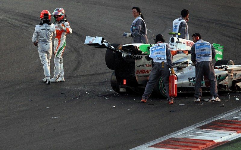 Mercedes GP's German driver Michael Schumacher and Force India's Italian driver Vitantonio Liuzzi  leave their car after they crashed at the Yas Marina circuit in Abu Dhabi, during the Abu Dhabi Formula One Grand Prix. (AFP)