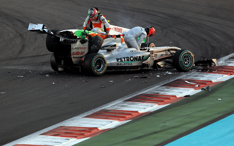 Mercedes GP's German driver Michael Schumacher and Force India's Italian driver Vitantonio Liuzzi  leave their car after they crashed at the Yas Marina circuit in Abu Dhabi, during the Abu Dhabi Formula One Grand Prix. (AFP)