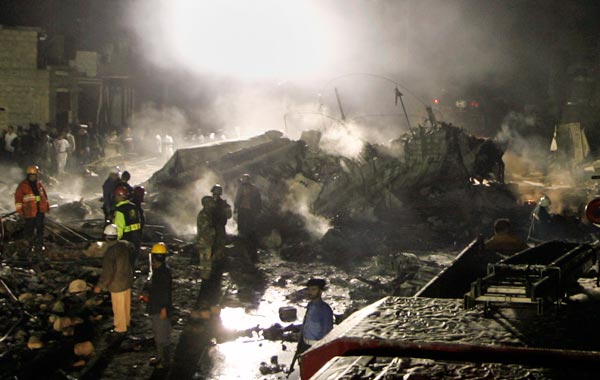 Pakistani security officials and firefighters examine the site of a plane crash in Karachi, Pakistan. (AP)
