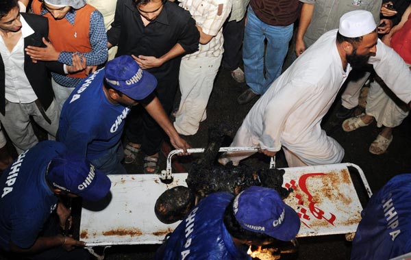 Pakistani medics evacuate a charred body after a Russian-made cargo plane crashed in a fireball seconds after taking off from the Karachi's airport early killing at least four people. (AFP)