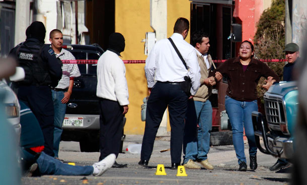 A woman is held back by police as she reacts while seeing a relative dead lying on the ground after he and another man were killed by gunmen in the northern border city of Ciudad Juarez, Mexico. With this incident, the city has reached the 3,000th homicide in 2010, surpassing the homicide count of the last two years. (AP)