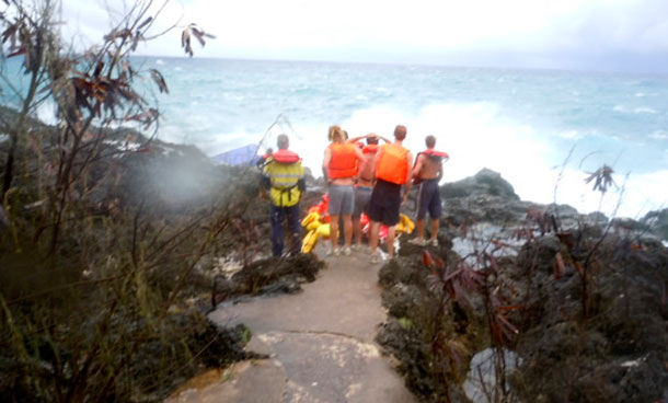 People watch from the rocky shore on Christmas Island during a rescue attempt as a boat breaks up in the background. A wooden boat packed with dozens of asylum seekers smashed apart on cliff-side rocks in heavy seas off an Australian island Wednesday, sending some to their deaths in churning whitewater. (AP)