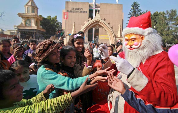 A man dressed as Santa Claus distributes sweets to children outside a church in Jammu, India. (AP)