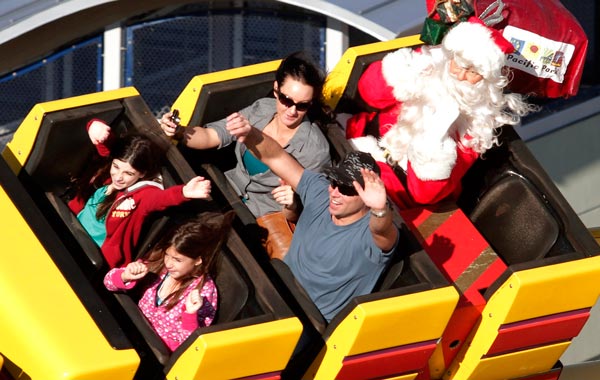 Visitors ride along with a life-sized figure of Santa Claus on a roller coaster at Pacific Park on the Santa Monica Pier in Santa Monica, Calif. (AP)