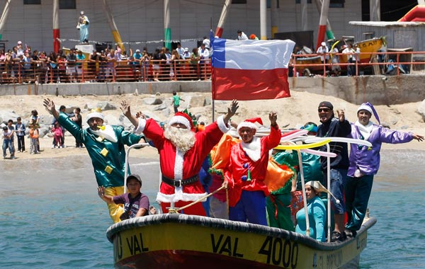 Ruben Torres, dressed in a Santa Claus outfit, and fishermen wave to people from a boat on Christmas Eve along the coast of Valparaiso city, about 75 miles (121 km) northwest of Santiago. (REUTERS)