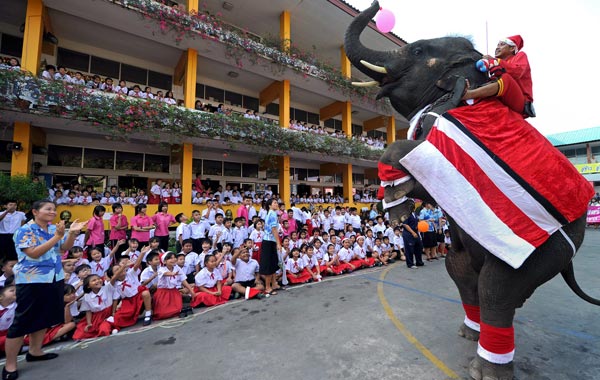 An elephant dressed in a Santa Claus costume performs by standing on its hind legs before giving out gifts to students to mark the Christmas season at a school in Ayutthaya province. (AFP)