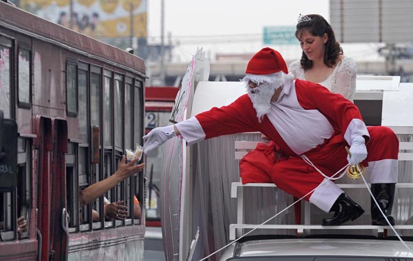 Thai hotel workers dressed in Santa Claus costumes while sitting on a decorated vehicle touring around to give out gifts to residents for Christmas in Bangkok. (AFP)