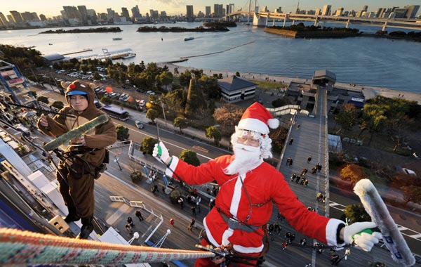 Workers in Santa Claus (R) and reindeer costumes clean windows outside of a 31-metre-high building at the Odaiba shopping mall on Tokyo's waterfront. (AFP)