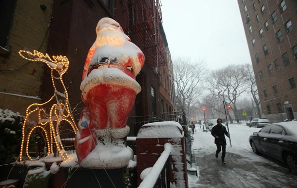 Snow falls on a lighted Santa Claus in Manhattan's East Village in New York City. (AFP)