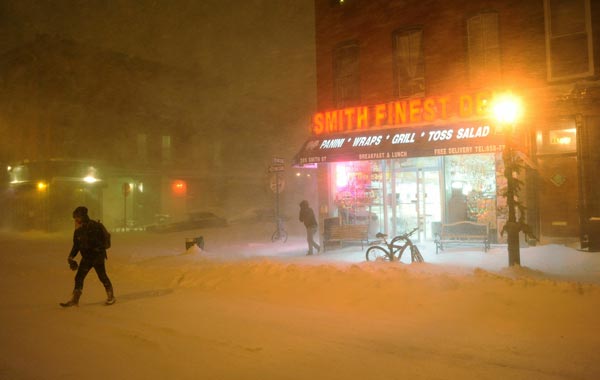 Pedestrians walk past a deli during a blizzard on in the Brooklyn borough of New York City. (AFP)