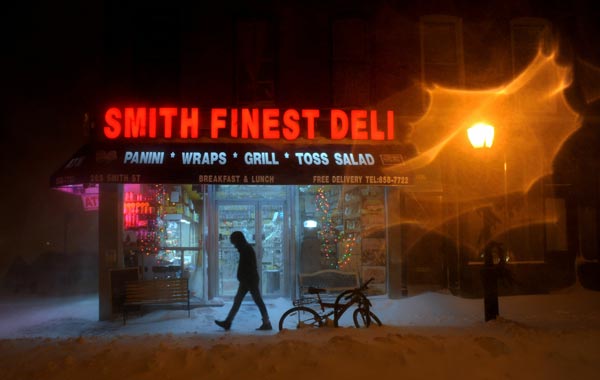 A pedestrian walks past a deli during a blizzard on in the Brooklyn borough of New York City. (AFP)