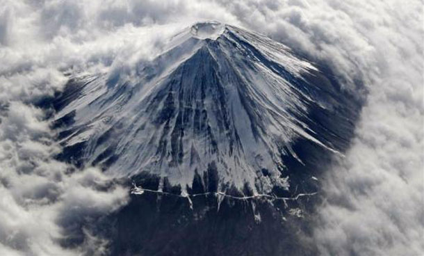 Japan's Mount Fuji, covered with snow and surrounded by cloud, is seen from an airplane. (REUTERS)