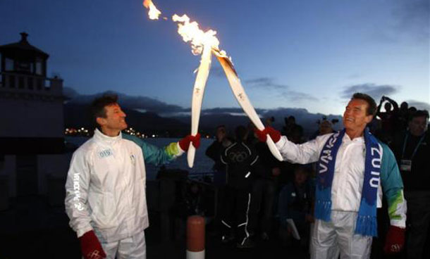 California Governor Arnold Schwarzenegger (R) passes the Olympic torch to London 2012 Olympic committee chairman Sebastian Coe in Stanley Park before the Vancouver 2010 Winter Olympics. (REUTERS)