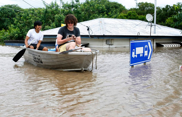 Residents paddle past a flooded house in the Brisbane suburb of Saint Lucia. Flood water in  Australia's third-biggest city peaked below feared catastrophic levels on Thursday but Brisbane and other devastated regions faced years of rebuilding and even the threat of fresh floods in the weeks ahead. (REUTERS)