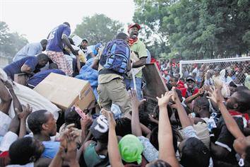 People climb up a food distribution truck in Port-Au-Prince. (REUTERS)