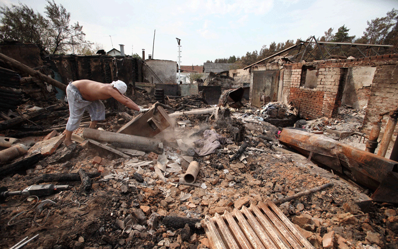 A Russian man moves debris inside the charred remains of his burnt out home in Voronezh on Wednesday. (AFP)