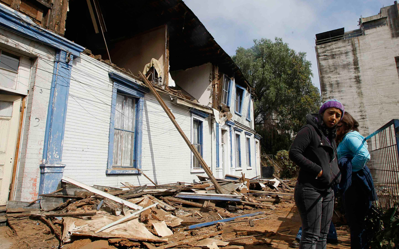 People stand outside a house destroyed in an earthquake in Valparaiso. A massive magnitude-8.8 earthquake struck south-central Chile early on Saturday, knocking down homes and hospitals, and triggering a tsunami. (REUTERS)