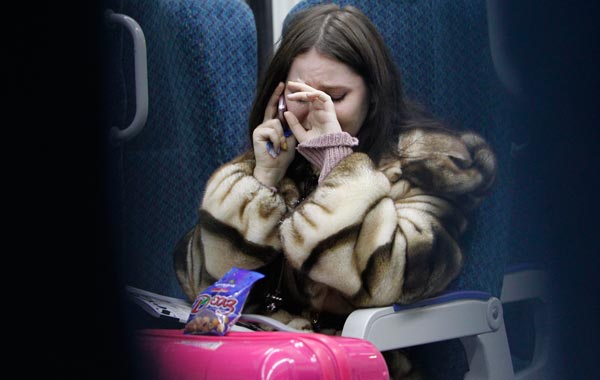 A woman cries while talking on the phone to an acquaintance who is at Domodedovo airport, as she travels by train to the airport from Moscow. (REUTERS)