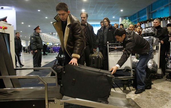 People entering Moscow's Domodedovo airport stand in line as they prepare to pass their belongings through a metal detector. (REUTERS)