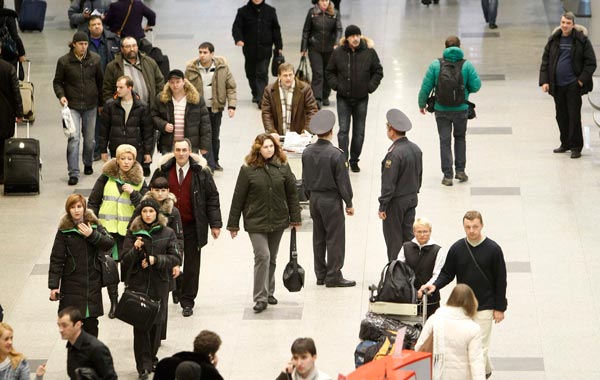 Interior Ministry officers stand guard, while people pass by, at Moscow's Domodedovo airpor. (REUTERS)