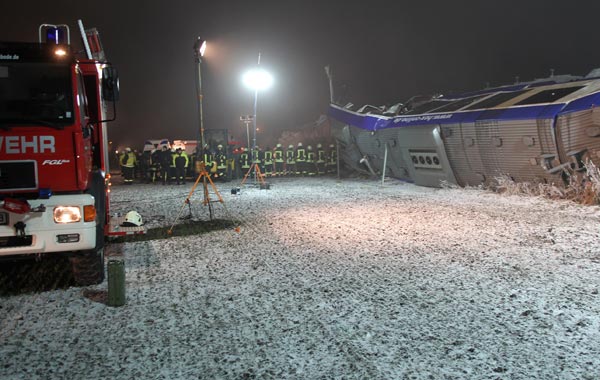 Fire fighters stand next to an overturned regional passenger train after it collided with a goods train. AFP)