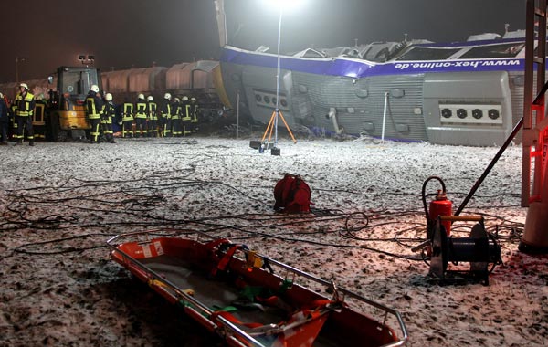 Fire fighters and an empty stretcher are seen next to an overturned regional passenger train after it collided with a goods train. (AFP)