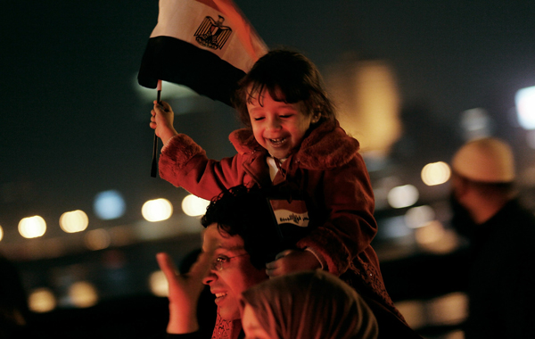 A girl laughs as she's hoisted on her father's shoulders on a bridge over the Nile river near Tahrir Square during a celebration over President Hosni Mubarak stepping down. (GETTY)