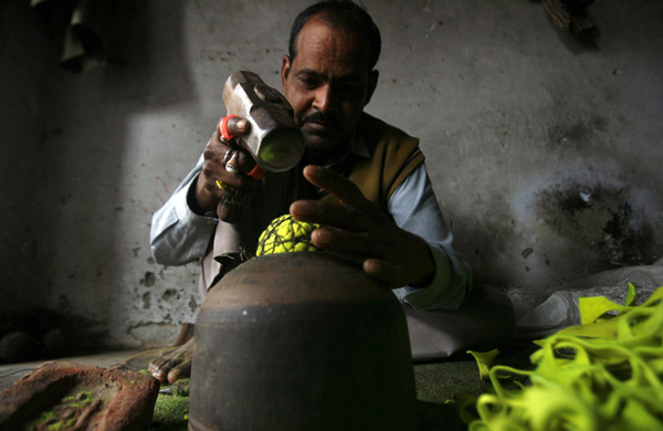 A worker uses a hammer to shape a cork wrapped with strings into a spherical core to make a cricket ball at a factory in Meerut, 80 km (50 miles) northeast of Delh. (REUTERS)