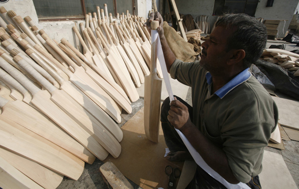 A worker wraps a cloth on the cane handle of a bat after its edges were filed to a smooth finish at a factory in Meerut, 80 km (50 miles) northeast of Delhi. (REUTERS)