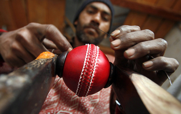 A worker stitches two leather halves together with a spherical core inside to form a cricket ball at a factory in Meerut, 80 km (50 miles) northeast of Delhi. (REUTERS)