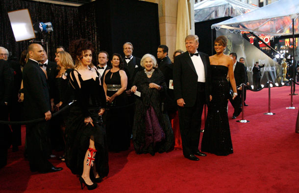 British actress Helena Bonham Carter (L), best supporting actress nominee for her role in "The King's Speech," shows off a Union Jack tied to her leg as US real estate magnate Donald Trump (C) and his wife Melania Trump (R) looks on at the 83rd Academy Awards in Hollywood, California. (REUTERS)