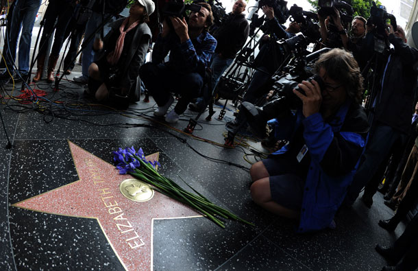 Reporters work as flowers are on Elizabeth Taylor's star on the Hollywood walk of Fame in Hollywood, California on March 23, 2011.  Actress Elizabeth Taylor died this morning at Cedars-Sinai Medical Center, reportedly of congestive heart failure. She was 79. (AFP)