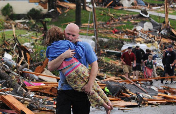 A man carries a young girl who was rescued after being trapped with her mother in their home after a tornado hit Joplin, Mo. on Sunday evening. The tornado tore a path a mile wide and four miles long destroying homes and businesses. (AP)