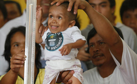 Pic 2: Junrey Balawing, 18, smiles as he stands next to a ruler being held by his mother Concepcion prior to the last of a series of measurements conducted by Guinness World Records at Sindangan Municipal Hall in Sindangan township, Zamboanga Del Norte province in Southern Philippines, Sunday June 12, 2011. (AP)