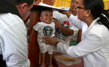 Junrey Balawing, center,  smiles as he is measured by Guinness World Records adjudicator Craig Glenday, left, for the last of a series of measurements conducted at Sindangan Municipal Hall, Sindangan township, Zamboanga Del Norte province in Southern Philippines, Sunday June 12, 2011, his 18th birthday and coincidentally the Philippines' Independence Day. (AP)