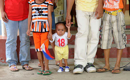 Filipino Junrey Balawing (C), who unofficially measures about 24 1/4 inches (61cm), poses for photographs with his family at a health centre in Sindangan town Zamboanga Del Norte in the southern Philippines on June 11, 2011. (AP)