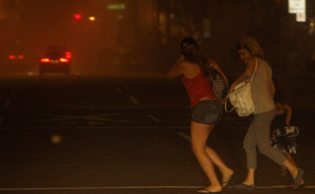 Pedestrians run to cross the street as they try to get away from a dust storm in downtown Phoenix, Tuesday, July 5, 2011.   A massive dust storm has swept into the Phoenix area and drastically reduced visibility across much of the valley.   (AP)
