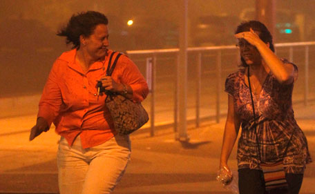 Mary Nichols and JoAnn Buckson, right, run for cover in Phoenix Tuesday July 5, 2011 as a dust storm blows through.  A massive dust storm has swept into the Phoenix area and drastically reduced visibility across much of the valley. (AP)