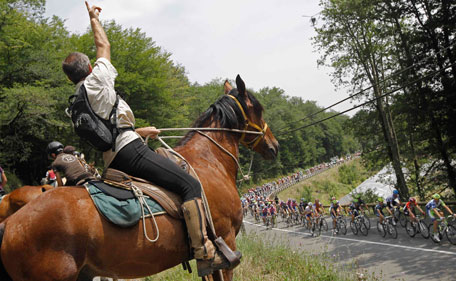 Spectators on horseback greet the riders in the pack during the 10th stage of the Tour de France cycling race over 158 kilometers (98.2 miles) starting in Aurillac and finishing in Carmaux, south central France, Tuesday July 12, 2011. (AP)