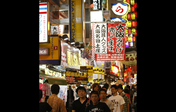 Osaka, Japan: Passers-by walk under advertisements in the Dotonbori shopping and amusement district in Osaka. (REUTERS)