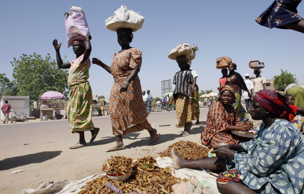 N'Djamena, Chad: Chadian women walk past fried locust sellers at a market in Chgoua in N'Djamena, the once war-torn capital of Chad. (REUTERS)