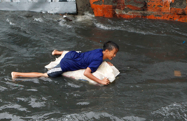 A boy drifts plays on a flooded street with a makeshift float in Las Pinas, Metro Manila. More than 100,000 families were displaced due to flooding, while 11 fishermen were missing in central Philippines as Typhoon Juaning battered the main Luzon island, forcing schools to close and grounding domestic flights and ferry services, disaster officials said on Tuesday. (REUTERS)