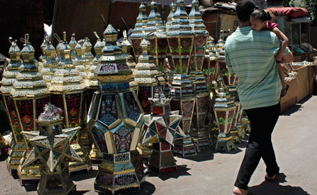 An Egyptian man carrying a child passes by traditional lanterns on display for sale at a street in Cairo, Egypt Monday, July 18, 2011. Egyptians shop for lanterns in preparation for the upcoming Muslims holy month of Ramadan beginning early August this year, to decorate their houses, shops and streets giving Egypt colorful and distinguished nights among the Islamic world. (AP)