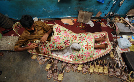 A Pakistani shoe maker, Hameed, sits inside a giant shoe at his shop in Lahore on July 25, 2011. Hameed has made a six feet (1.83m) shoe with gold thread to attract his customers for an upcoming Muslim festival known as 'eid', the selling price of the shoe is approximately USD 350 (Dh1,285). The 'eid' festival usually takes place at the end of the fasting month of Ramadan, which begins in the month of August this year. (AFP)