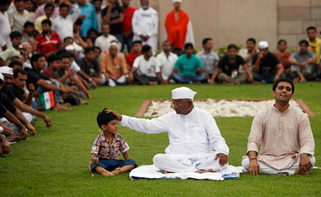 Supporters watch as Indian rights activist Anna Hazare, center, with a child at Rajghat, India, Monday, Aug. 15, 2011. Hazare announced he will resume his hunger strike on Tuesday against corruption. Delhi police on Monday denied Hazare permission for his hunger strike, but supporters said they will fast anyway and risk arrest. (AP)