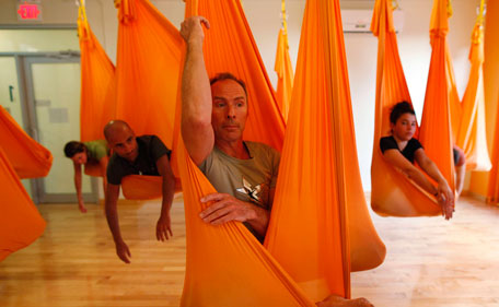 Antigravity Inc. founder Christopher Harrison (C) sits in a hammock as he conducts a class of "antigravity" yoga class at the Om Factory in New York August 16, 2011. "Antigravity" yoga makes use of hammocks to help practitioners gain greater flexibility, allowing for a wider range of yoga poses, according to the workshop's website.(REUTERS)