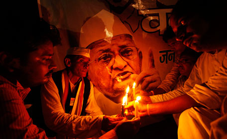 Supporters of Indian anti corruption activist Anna Hazare hold a candlelight vigil in front of a picture showing his image in Allahabad, India, Tuesday, Aug 16, 2011. Hazare arrested Tuesday for planning a public hunger strike began his fast behind bars as his supporters held protests across the country, with thousands detained by police. (AP)