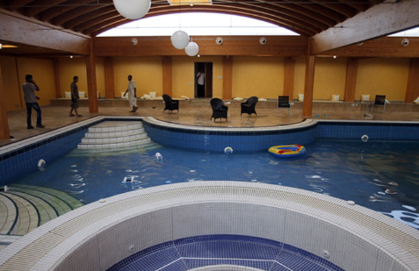 Rebel fighters and civillians walk near the swimming pool inside the house of Aisha Gaddafi, the daughter of Libyan dictator Moammar Gaddafi, in Tripoli, Libya. (AP)