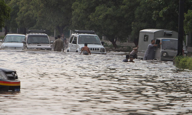 Vehicles drive through a flooded road caused by heavy monsoon rainfall in Karachi, Pakistan on Saturday, Sept 10, 2011. (AP)